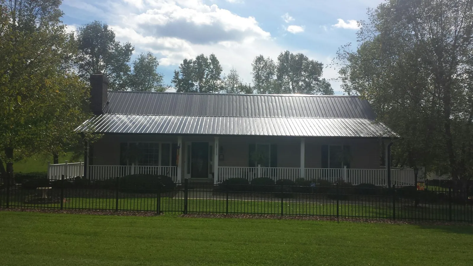 Gray metal roof on a brick ranch with a full width front porch — Gutter Guard Installation work by our crew in Neskowin