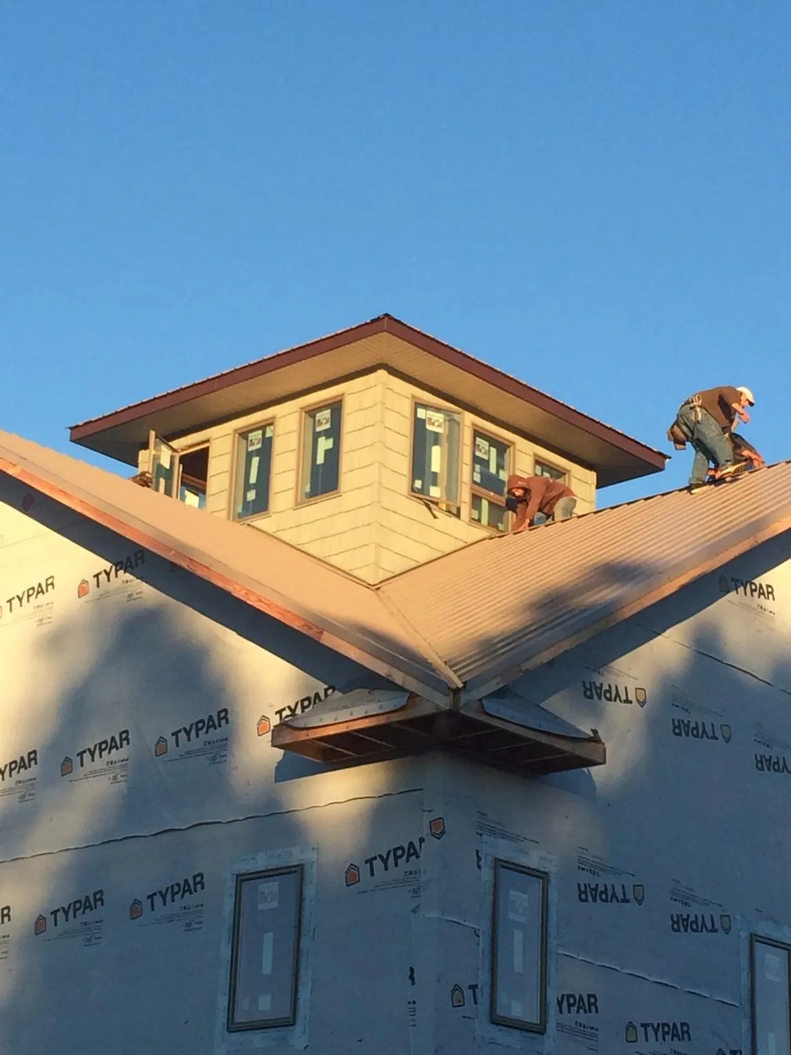 Roofers working around a rooftop cupola on a new metal roof at sunset — Roof Waterproofing in Neskowin by Roofing Brothers